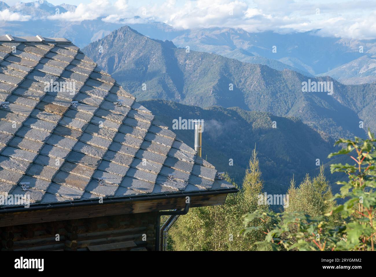 roof with stone tiles, typical of mountain house houses, blue gray granite stones, mountains in background. thermal insulation, energy class. Stock Photo