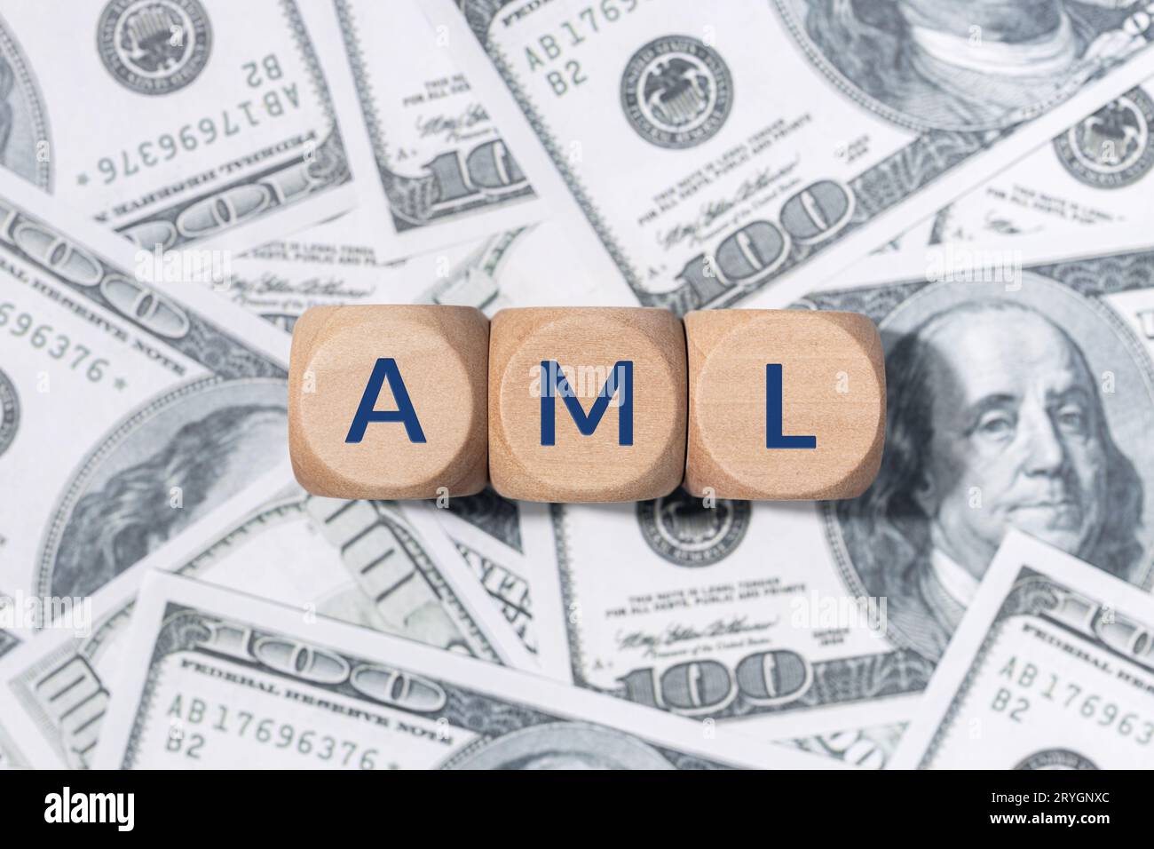 AML word on wooden blocks and US dollar bills background. Anti money laundering concept Stock Photo