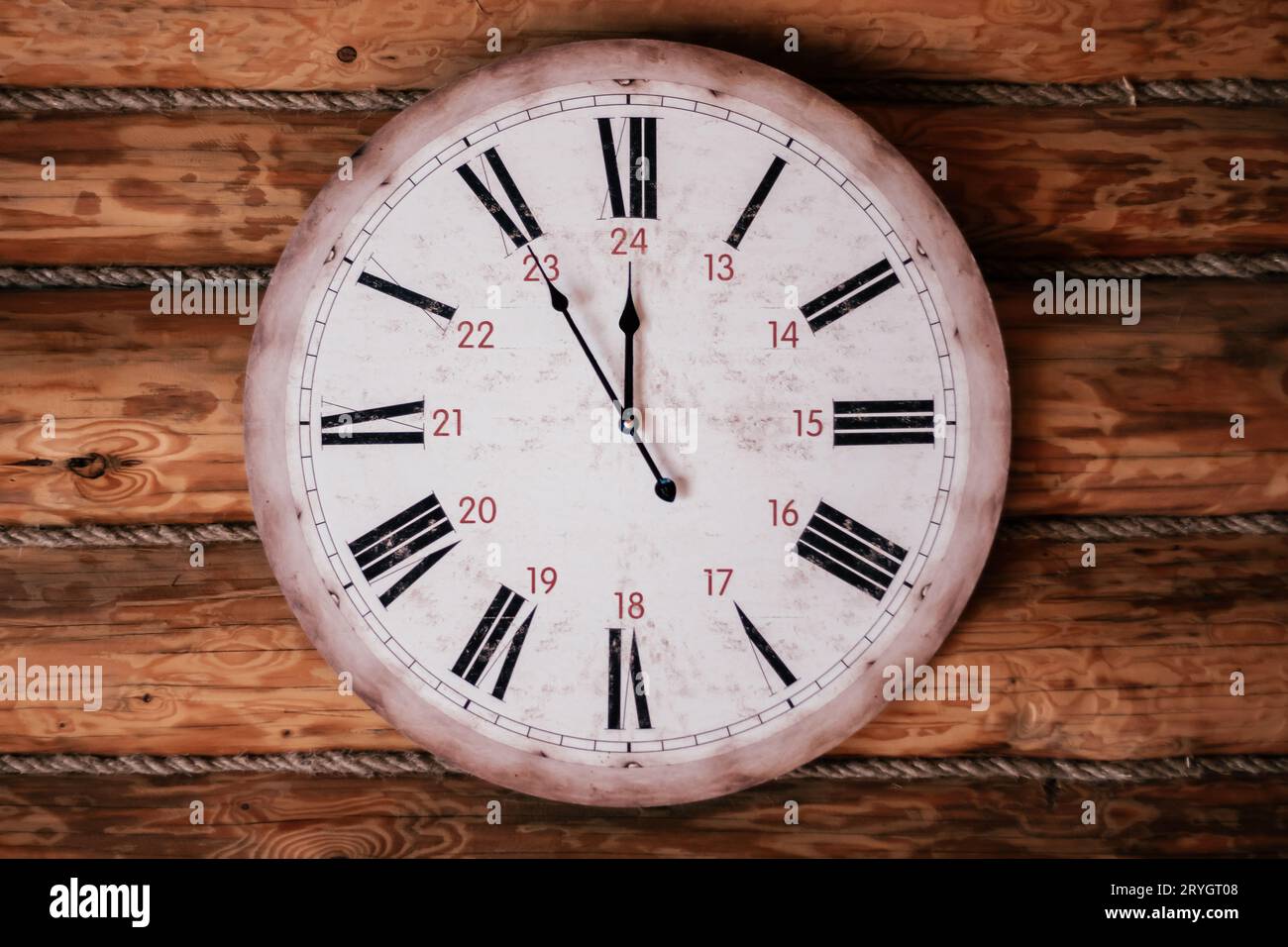 Round vintage clock showing five minutes to noon, midnight hangs on wooden wall. Decorative elements. Countdown. Design. Cozy house . Retro style. Sen Stock Photo