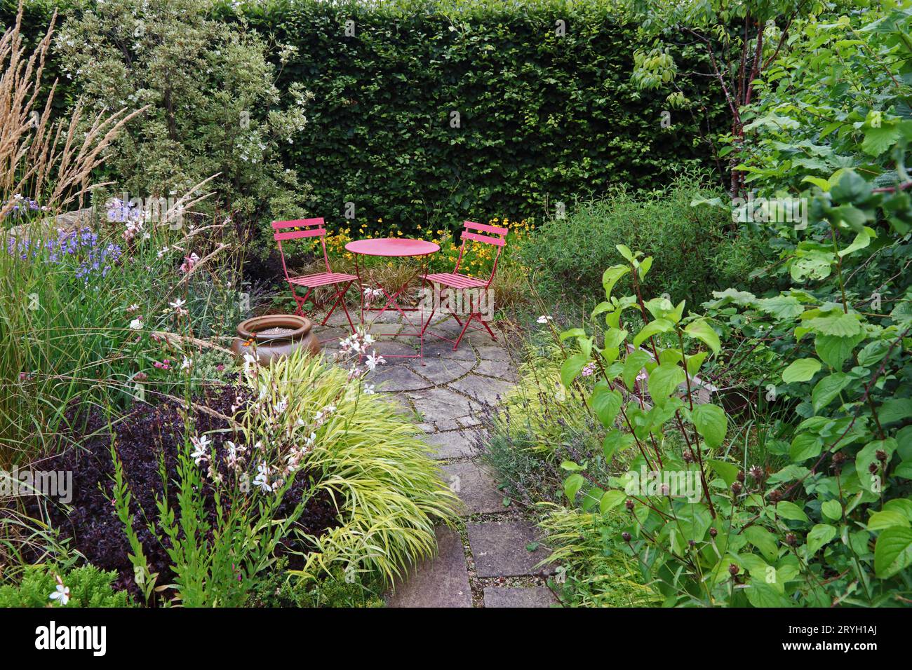Red, metal table and chairs is small garden Stock Photo Alamy
