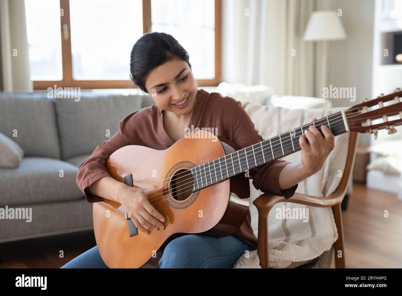 Smiling Indian woman playing acoustic guitar at home Stock Photo Alamy