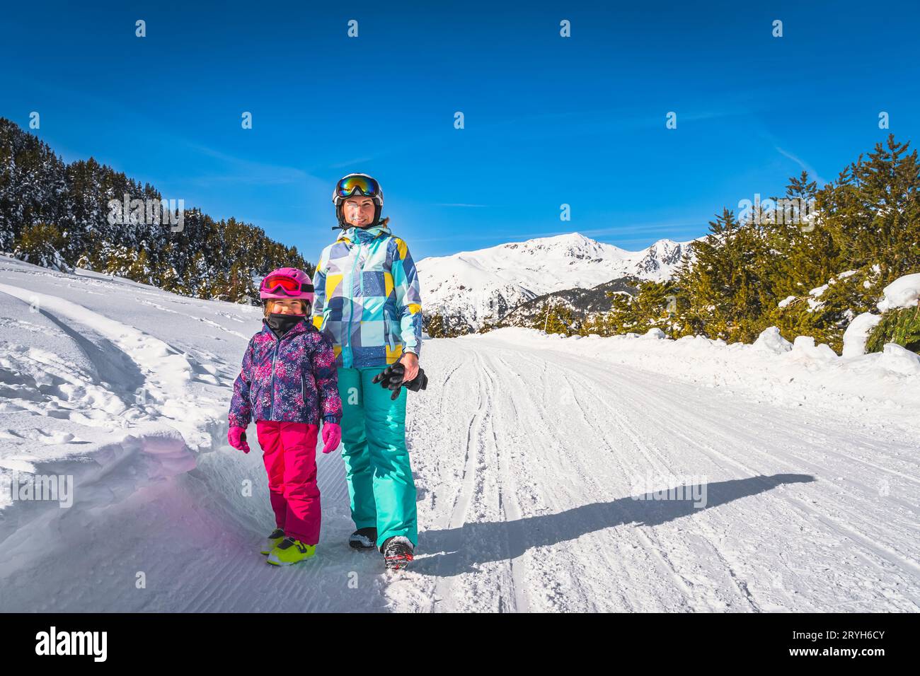 Mother and daughter, family, standing on a snowy road with forest and