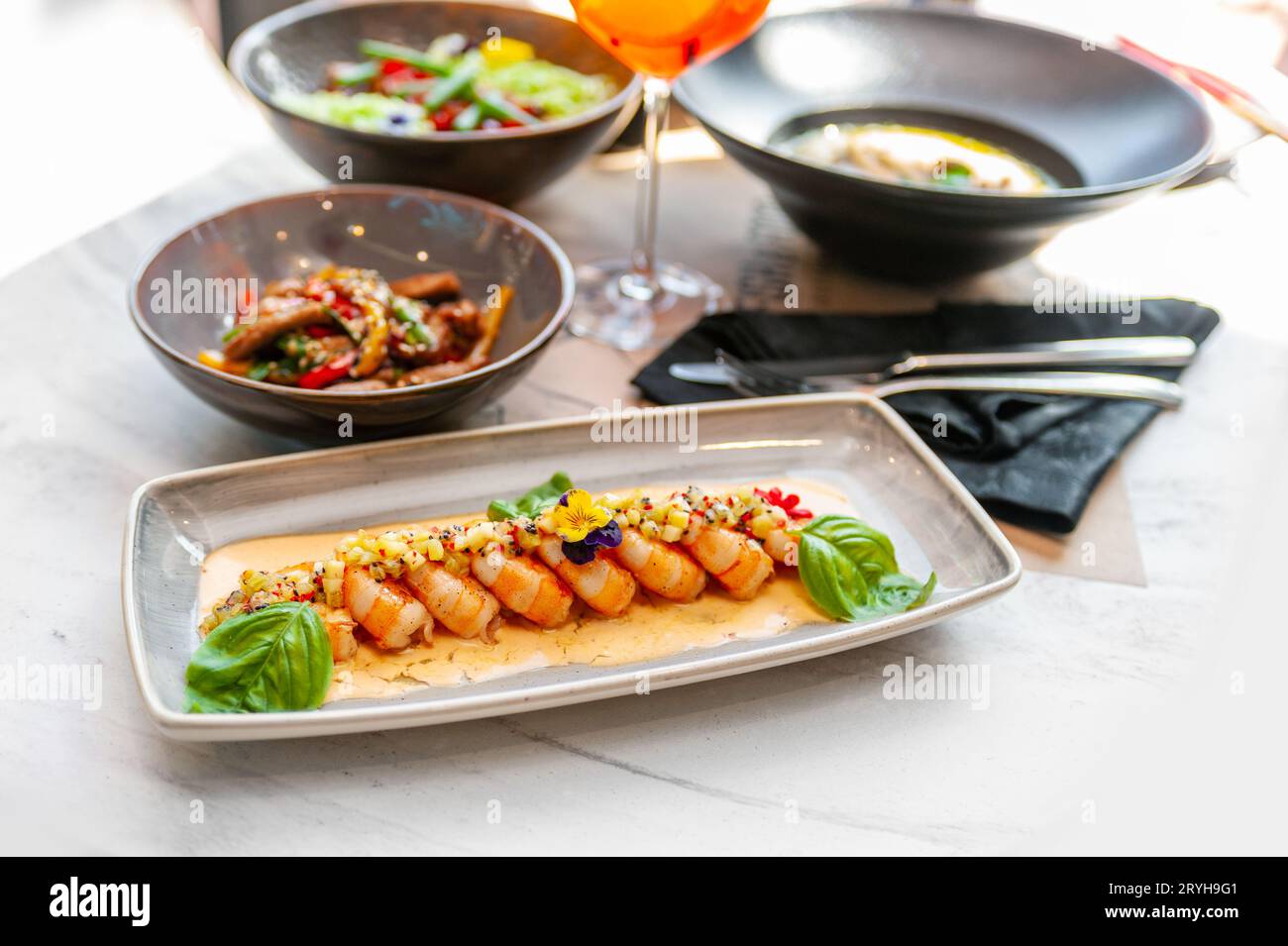 Fried shrimp in creamy sauce with mango and basil on a gray plate in a restaurant. High quality photo Stock Photo