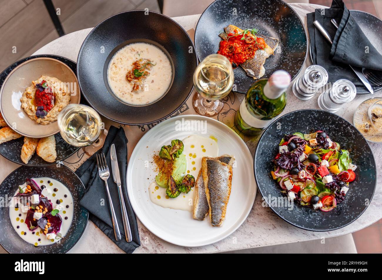 A set of Mediterranean cuisine dishes on a table in a restaurant with a glass and a bottle of white wine. View from above. High quality photo Stock Photo