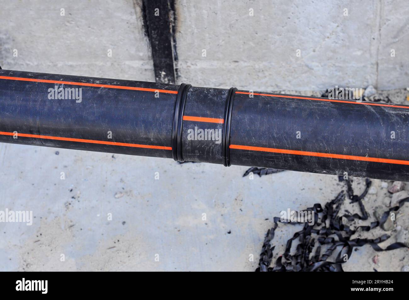 Soldered joint of black plastic pipe for soil heating, against the background of concrete and
