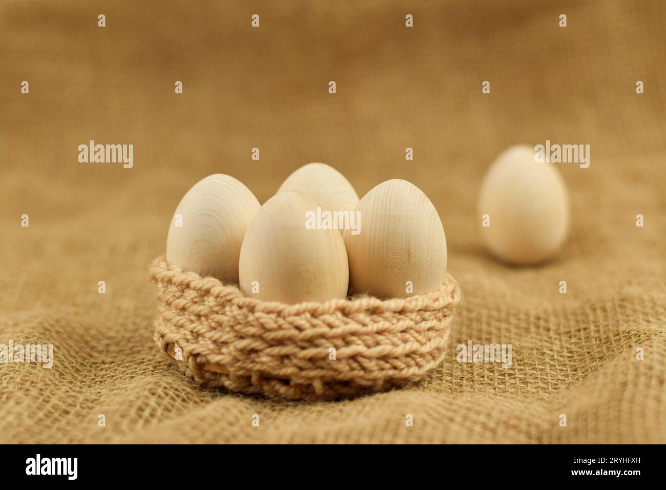 Decorative wooden Easter eggs in a wicker basket. Chicken eggs closeup on a vintage background. Zero waste easter. Stock Photo