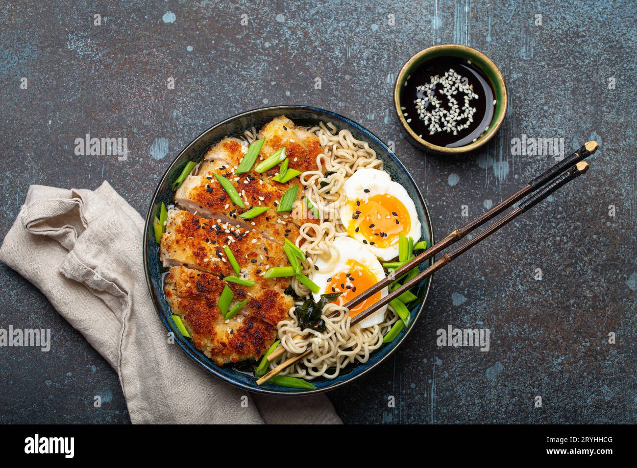 Asian noodles ramen soup with deep fried panko chicken fillet and boiled eggs in ceramic bowl