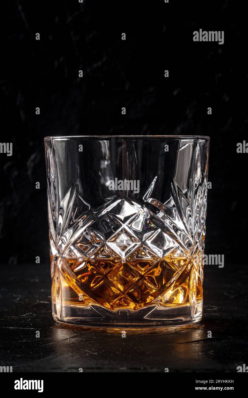 Whiskey in a glass with ice. Bourbon whisky on rocks on a dark stone background Stock Photo