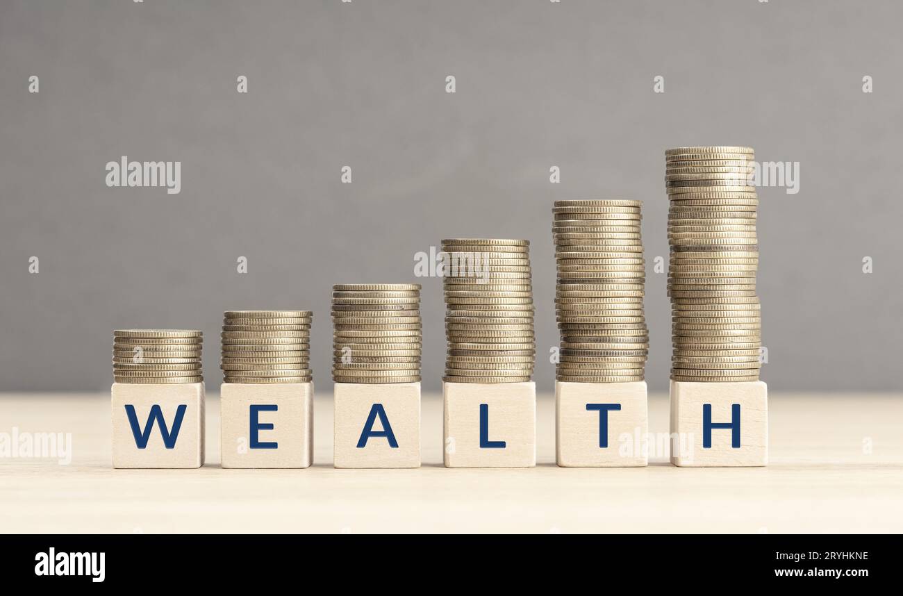 Wealth concept. Wooden blocks with text and stacks of coins that incrementally increase, effectively showcasing the accumulation Stock Photo
