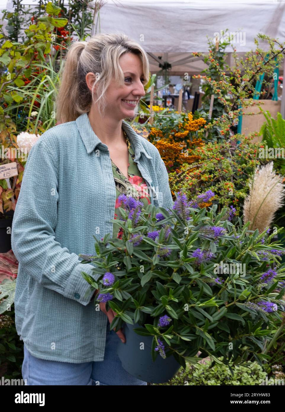 A woman selling a hebe plant at the Chiswick Flower Market held on the first Sunday of every month.  Chiswick West London Stock Photo