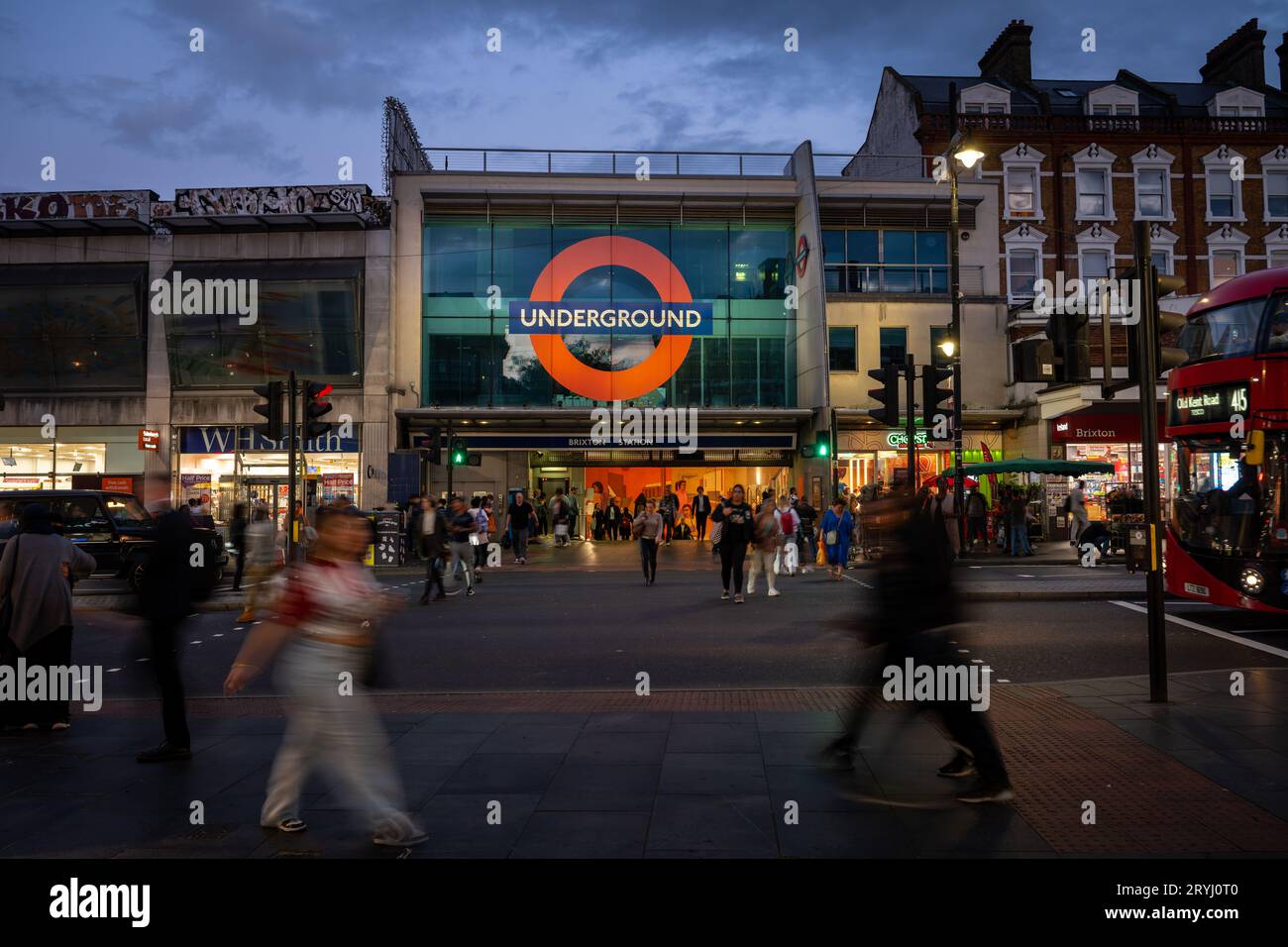 Brixton, London, UK: Pedestrian crossing on Brixton Road opposite Brixton underground station. Evening view with people and traffic. Stock Photo