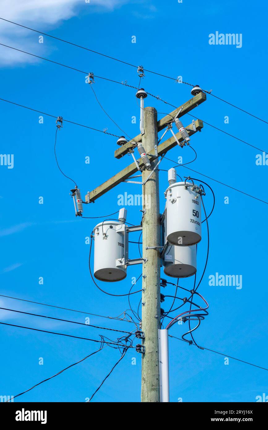 Wooden electricty pole with mounted transformators on blue sky background Stock Photo
