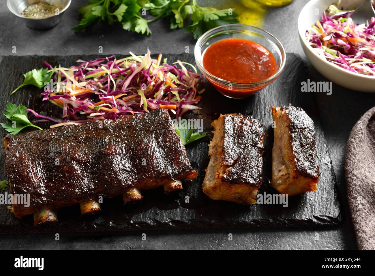 Spicy grilled spare ribs on board on dark stone background. Close up view Stock Photo