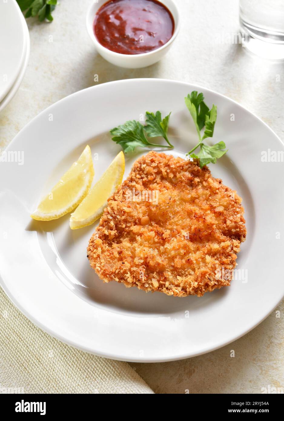 Homemade breaded chicken schnitzel on plate over light stone background. Close up view Stock Photo