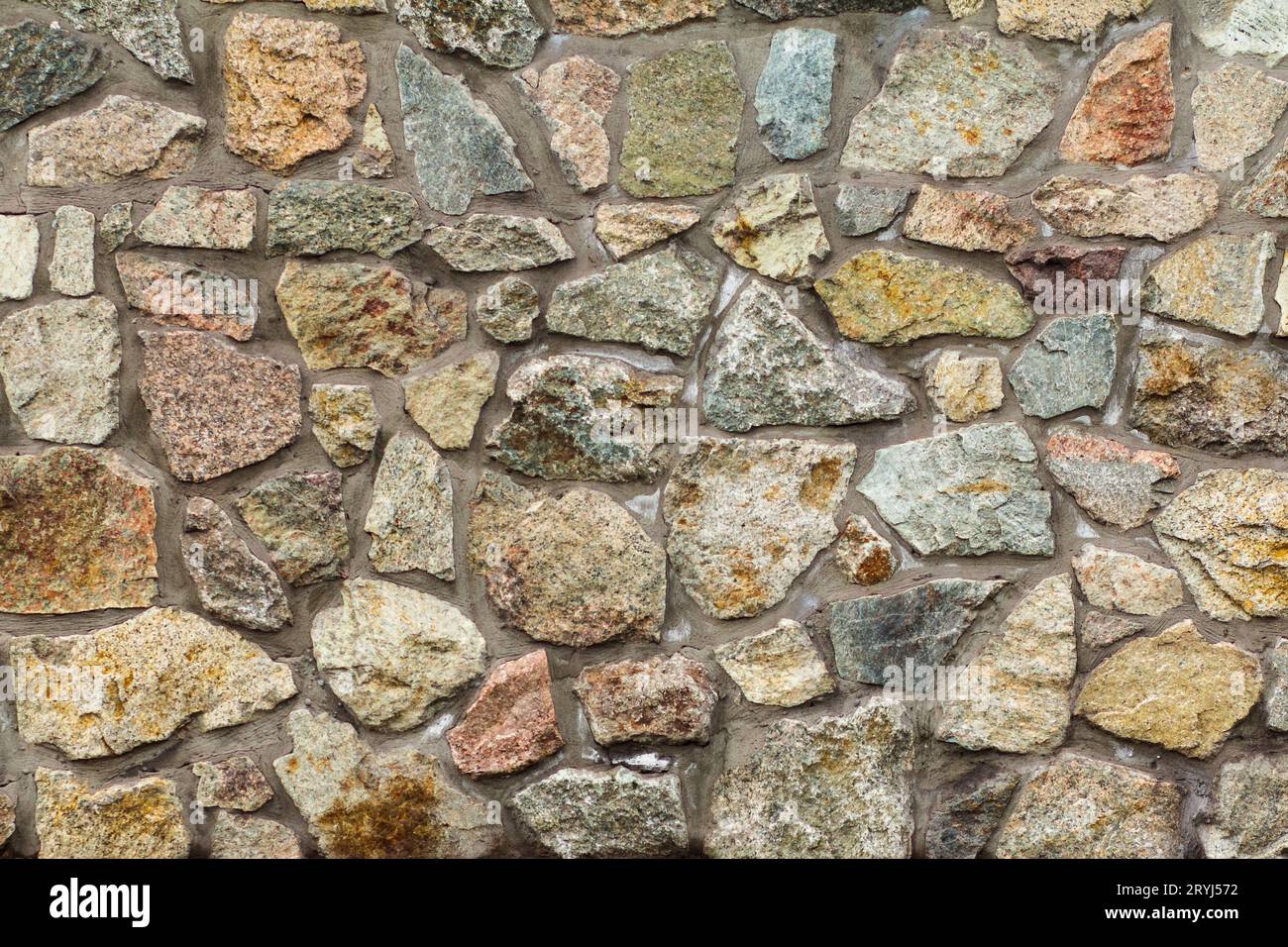 Front view of gray stone wall with cement solution. Stock Photo