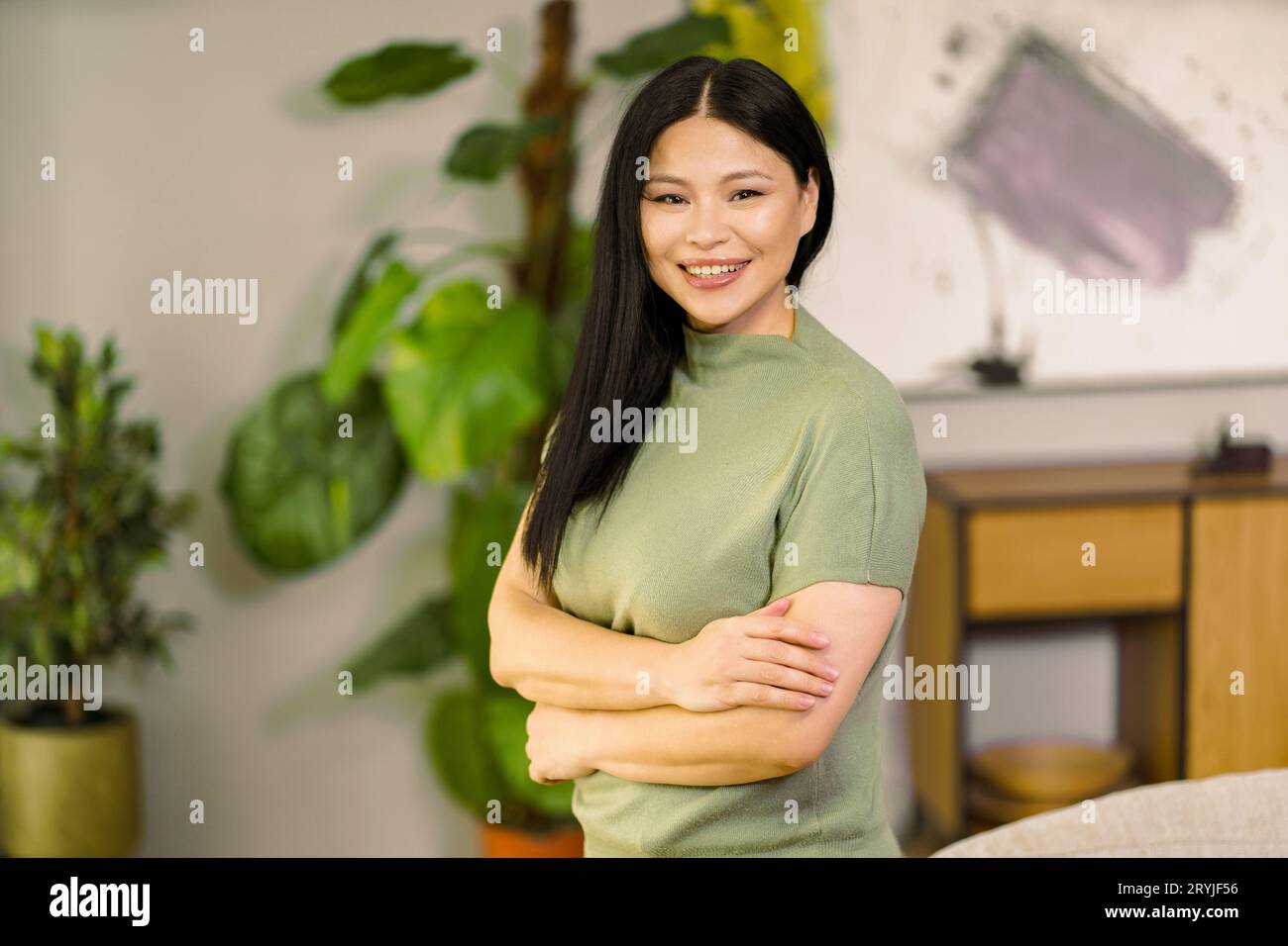 Middle-aged woman smiles with vibrant energy at home, embodying the concepts of healthy lifestyle and biohacking, promoting well Stock Photo