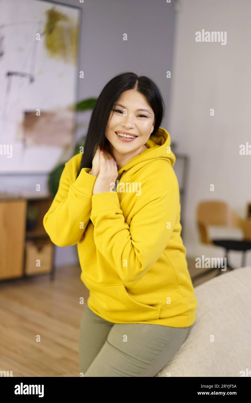 Mature Asian woman is captured in her home, enjoying the happy moments of life through the lens of lifestyle biohacking. She is Stock Photo