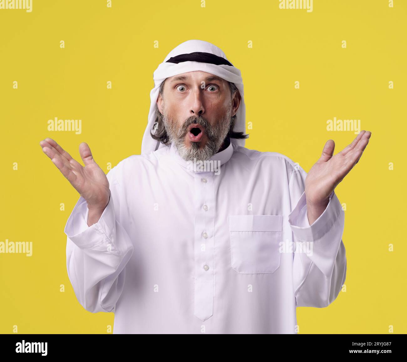 Surprised Arab man in traditional Dishdasha clothing raises both hands