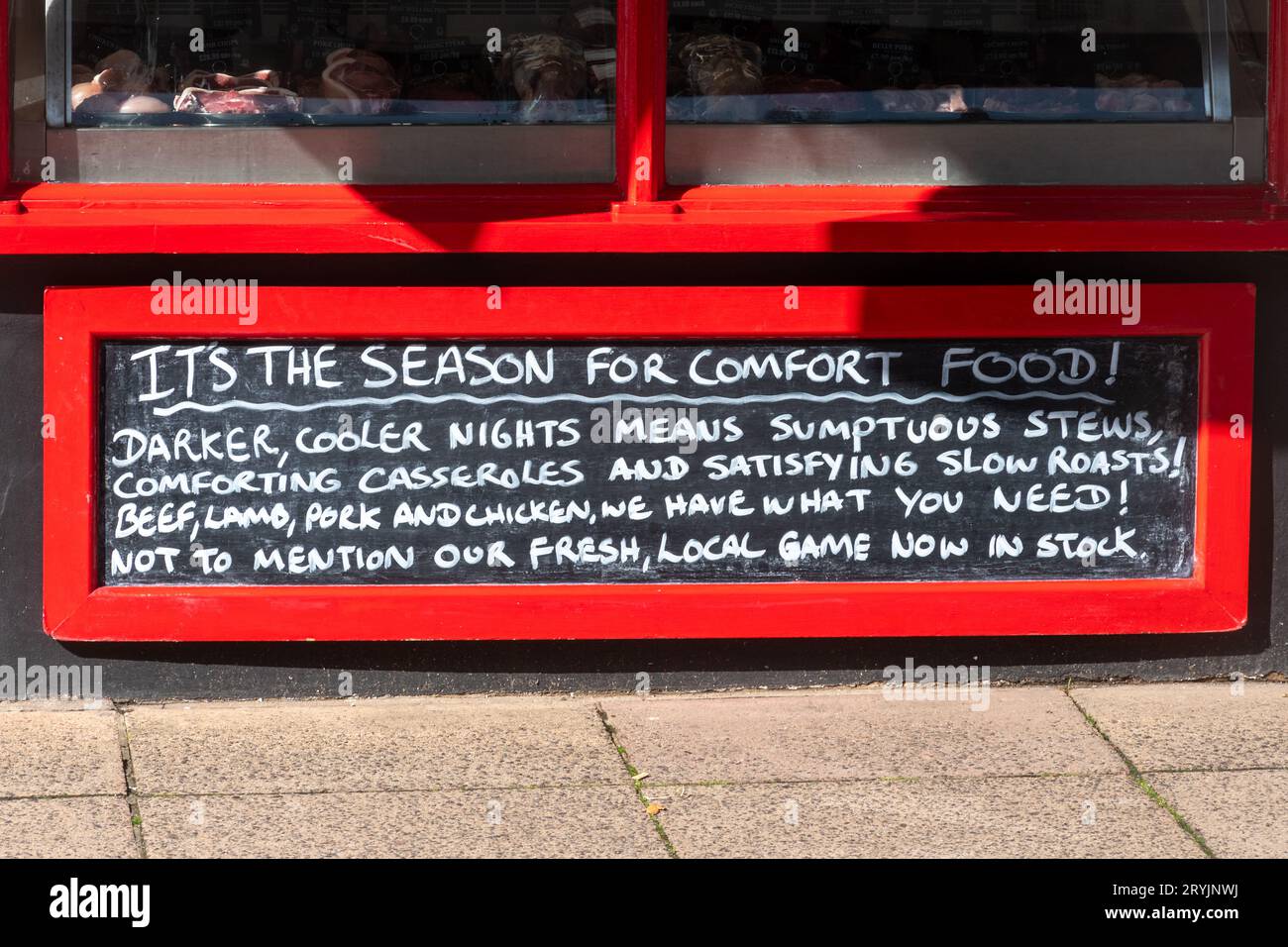 Sign in butchers shop 'Its the season for comfort food' promoting stews, casseroles, roasts, meats for cooler weather in autumn, England, UK Stock Photo