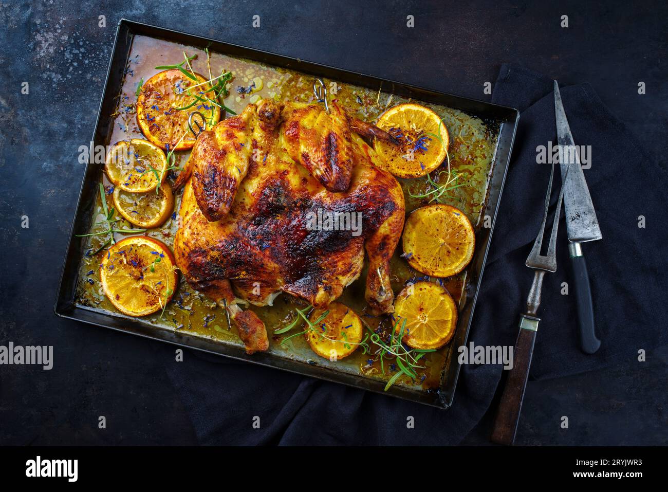 Traditional barbecue spatchcocked chicken al mattone chili with orange slices and herbs served as top view on an old rustic meta Stock Photo