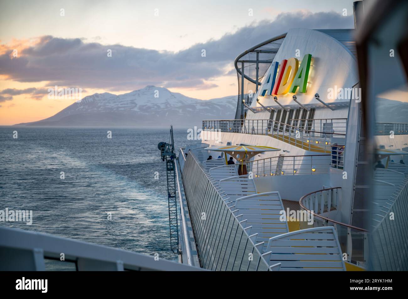 AIDA Bella on the sea in front of Iceland with snow mountain in background, Colorful Aida Logo and cruise ship in front Stock Photo