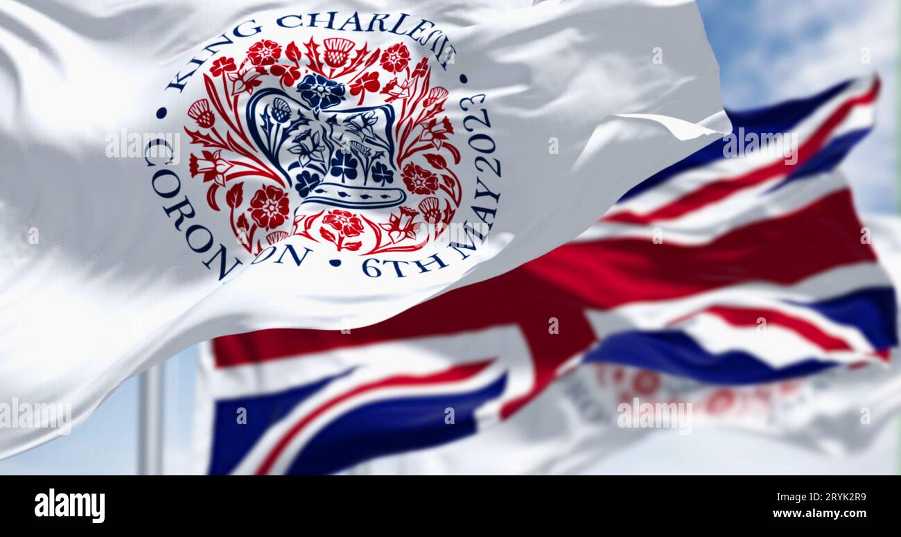 Flags with the emblem of the coronation of King Charles III and of UK waving Stock Photo
