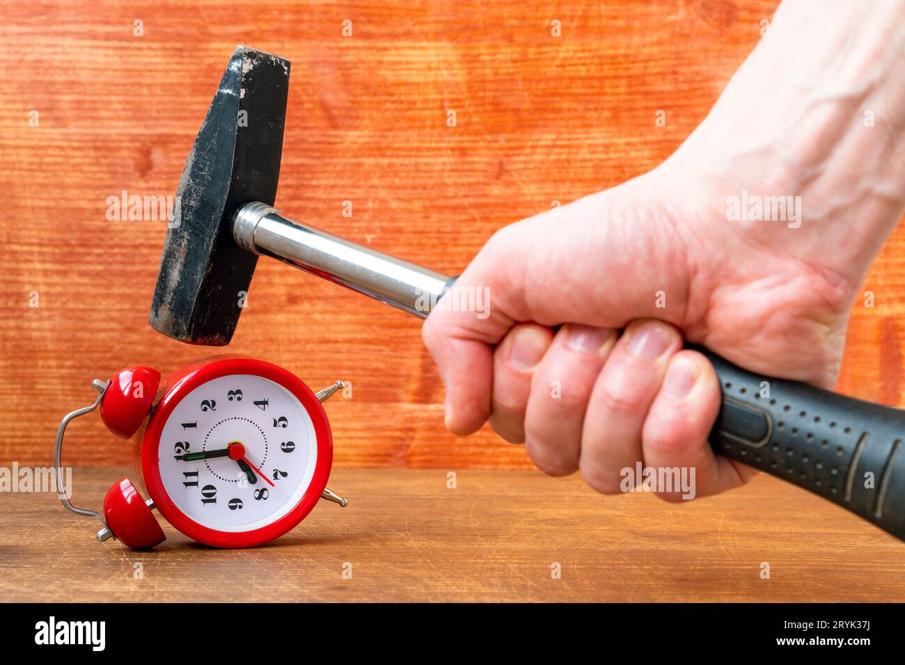 A man smashes an alarm clock with a hammer Stock Photo