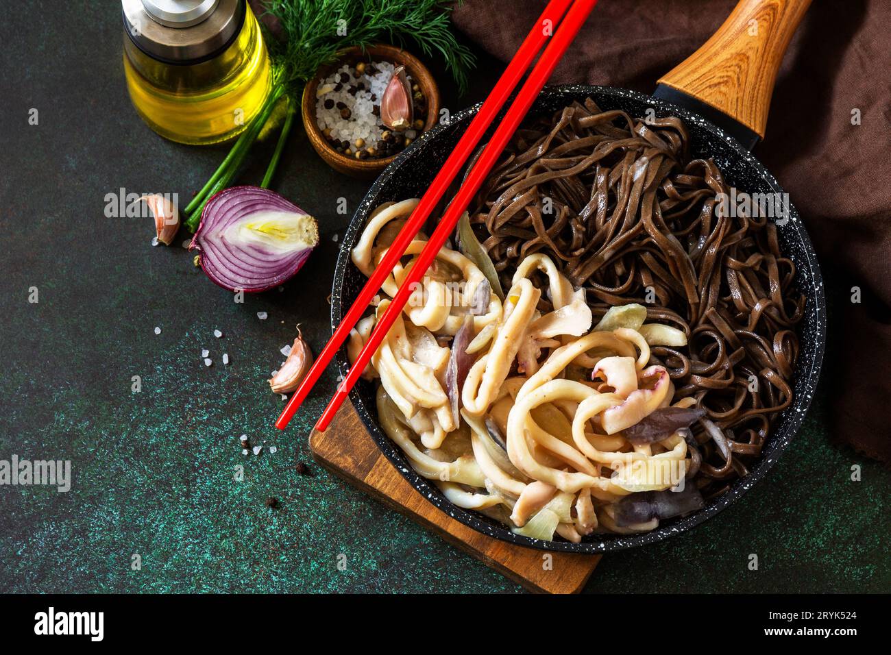 Spicy Noodles, Korean traditional food. Buckwheat soba noodles and squid with sour cream sauce on a dark stone table top. Stock Photo