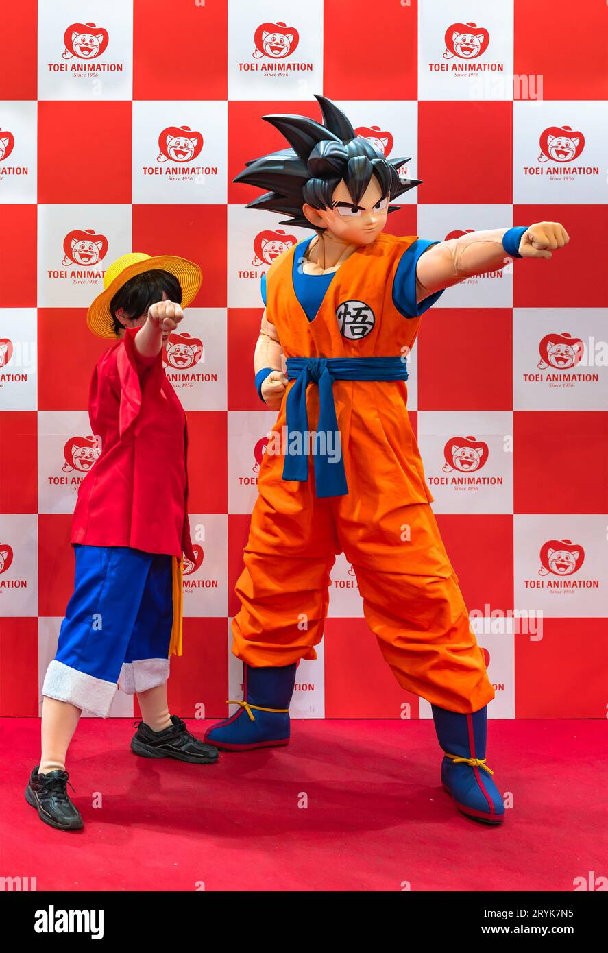 chiba, japan - dec 18 2022: One young girl cosplayer wearing the luffy character costume from One piece swinging one's fist forward with Son Goku Stock Photo