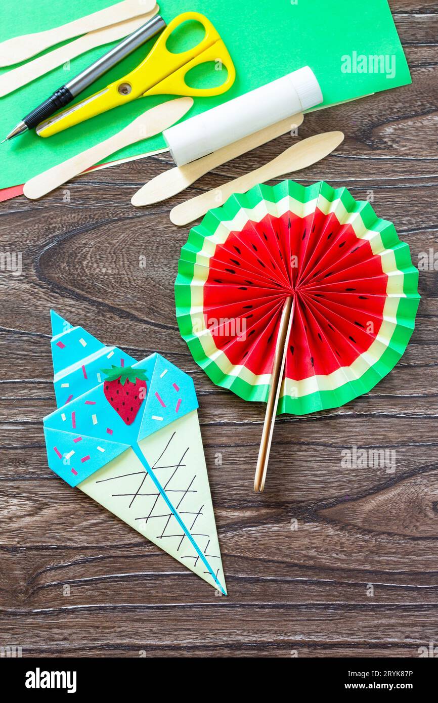 Paper Fan watermelon and origami paper ice cream, summer toy wooden sticks on a wooden table. Childrens art project, handmade, c Stock Photo