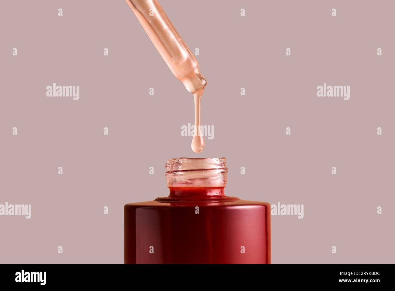 A drop of pink cosmetic drips from the dropper. Stock Photo