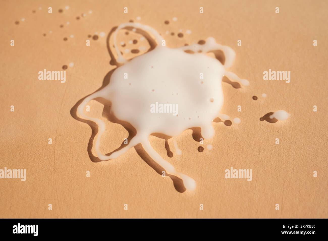 A splattered drop on a beige background. Stock Photo