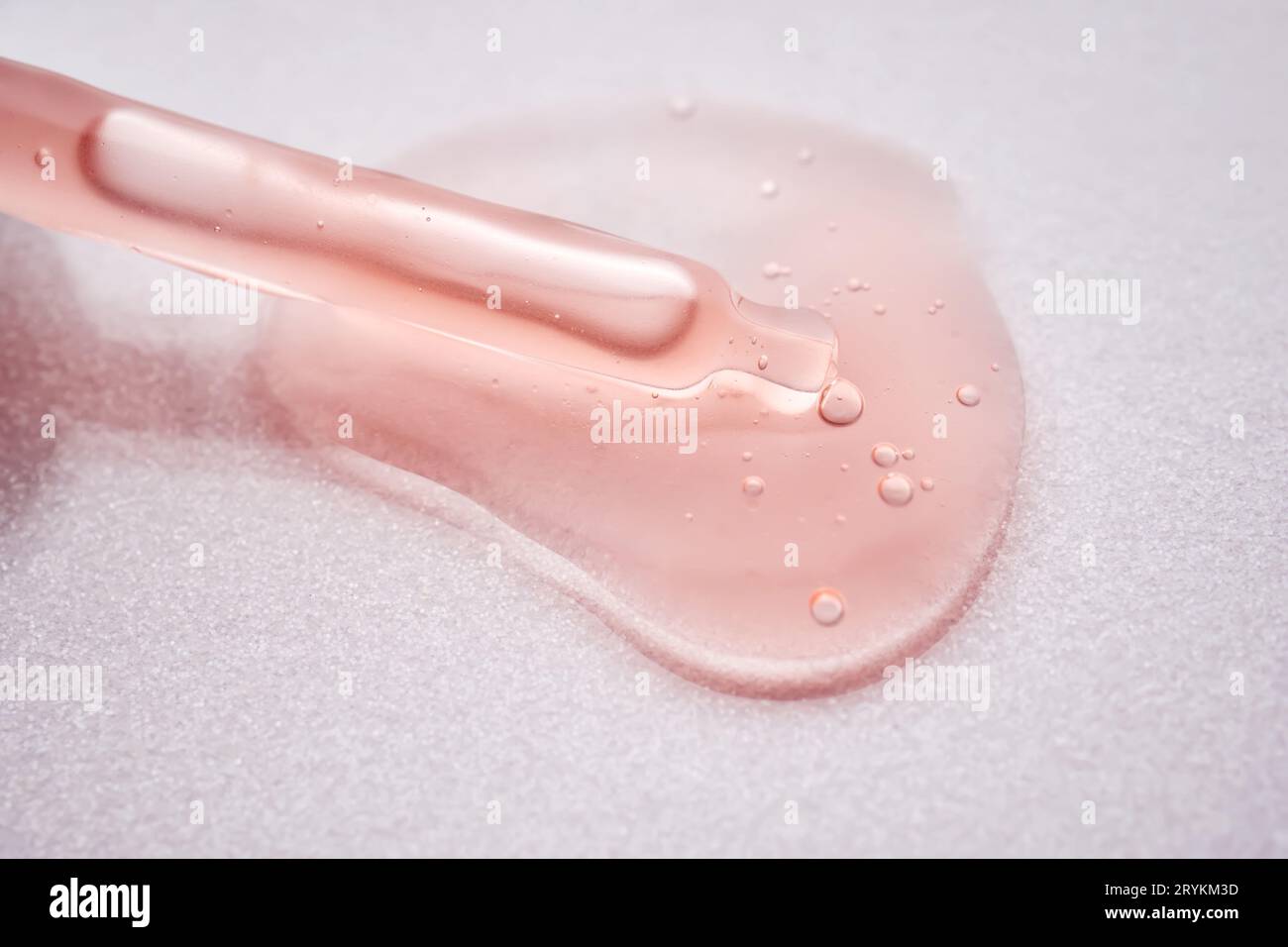 A pipette with a viscous pink cosmetic lies in a drop. Stock Photo