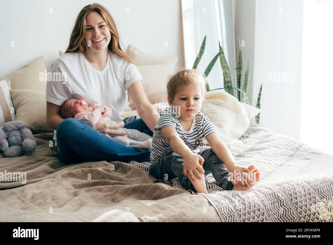 Mom with children on the bed. The baby is in mom's arms Stock Photo - Alamy