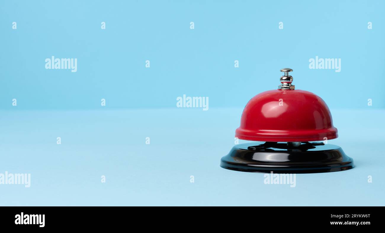 Metallic red bell to call staff on a blue background Stock Photo