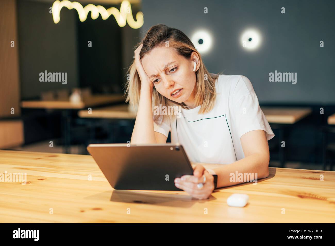 Upset stressful woman looks at the screen of a digital tablet. Disappointment at work Stock Photo