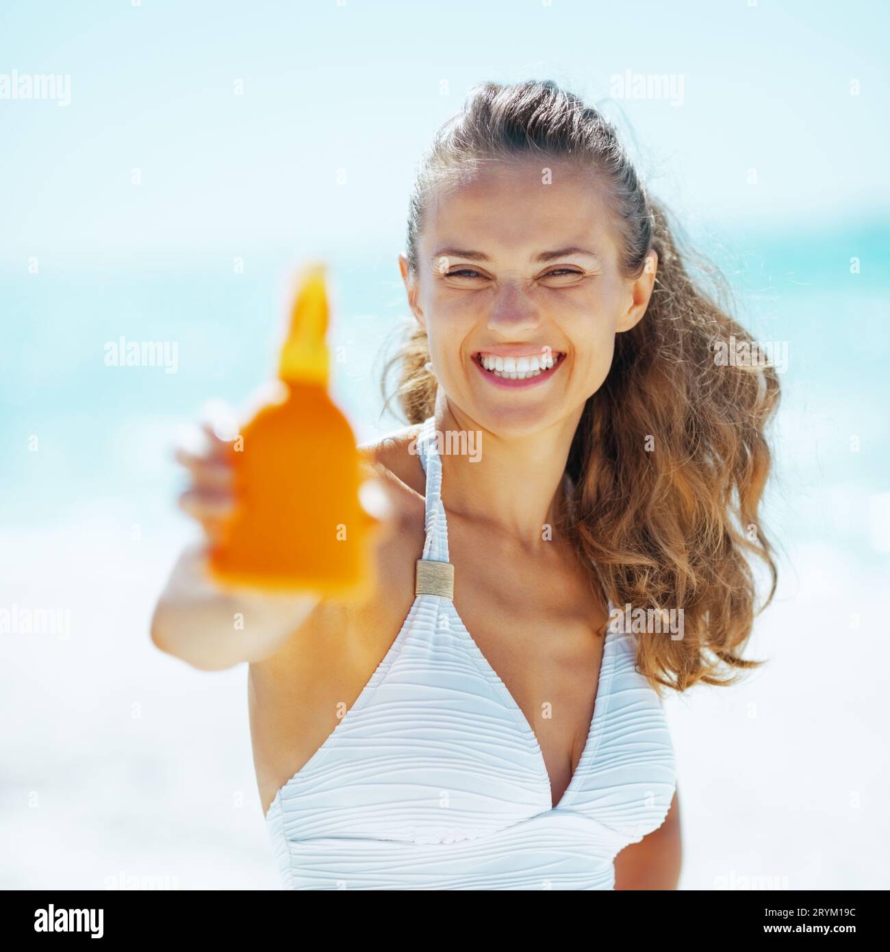 Happy young woman showing sun screen creme Stock Photo