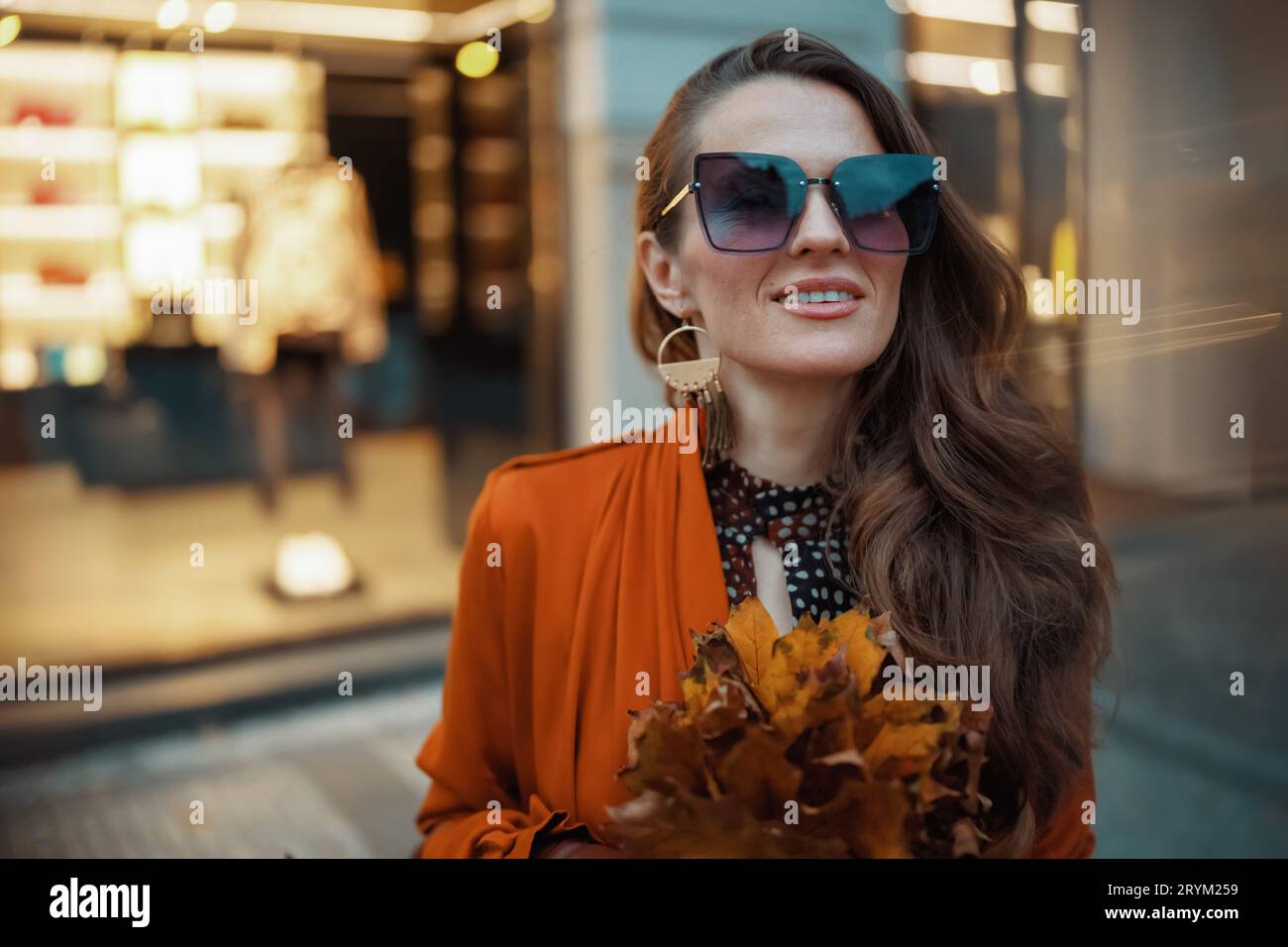 Hello september. modern middle aged woman in orange trench coat with ...