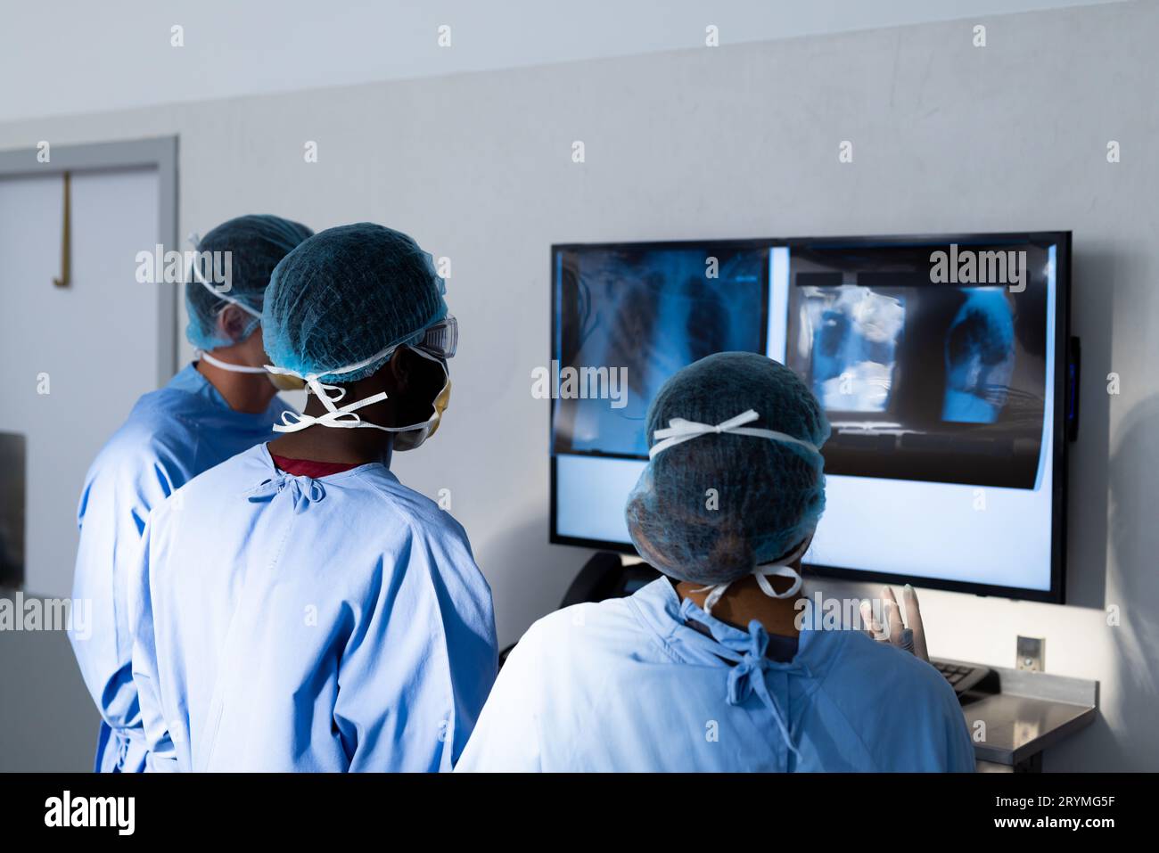 Diverse group of surgeons discussing x rays on screen in operating theatre Stock Photo