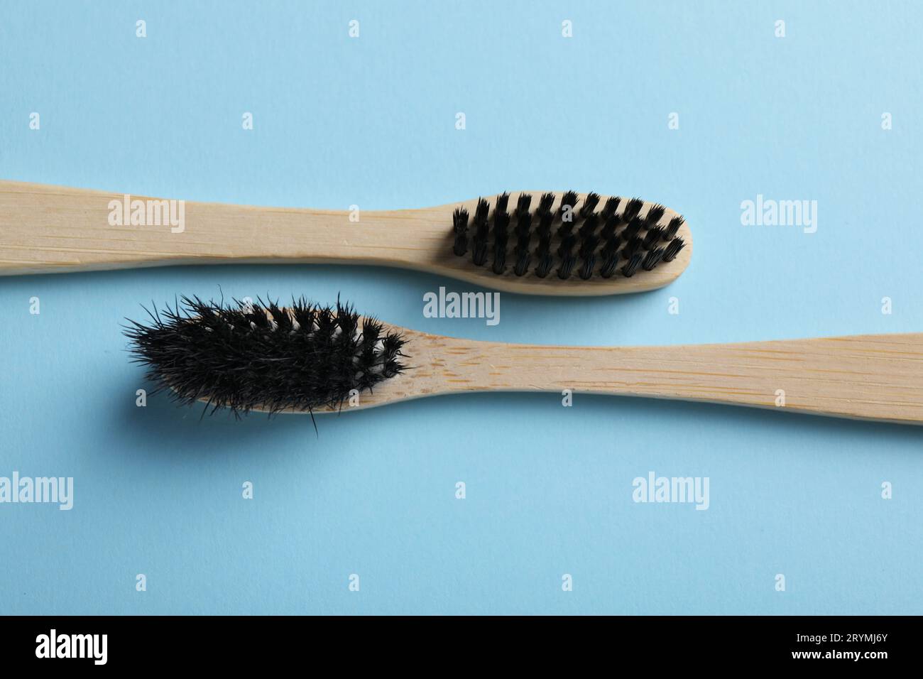 Two bamboo toothbrushes on light blue background, flat lay Stock Photo