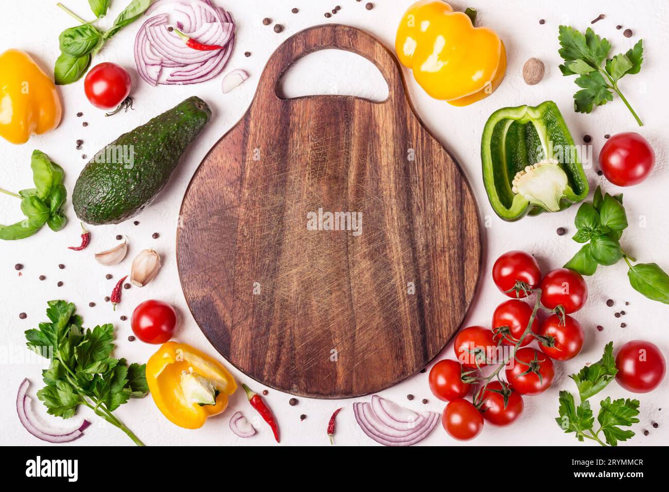 Set of vegetables and herbs around a wooden cutting board. European cuisine and cooking concept Stock Photo