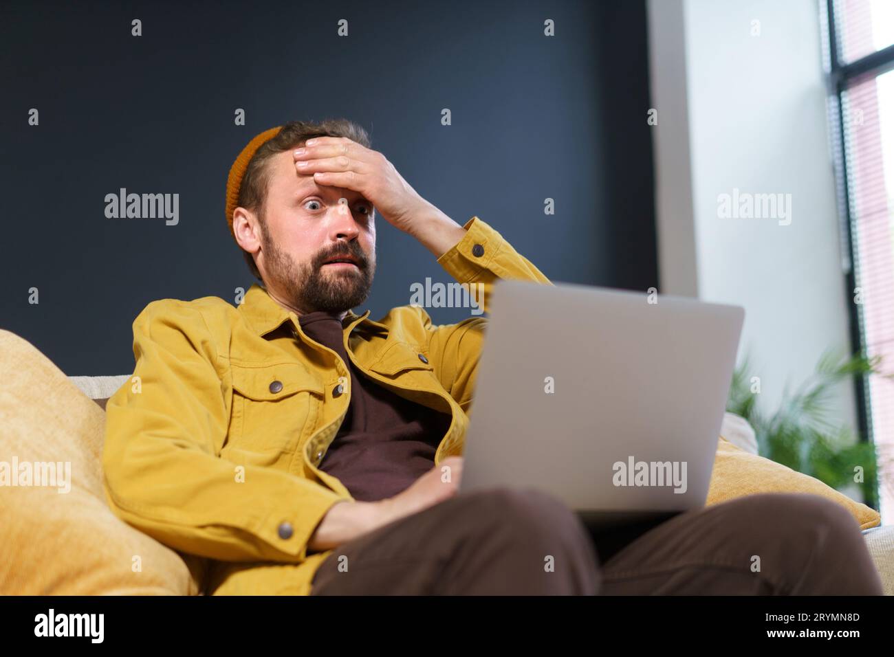 Shocked user's reaction to online content he discovered on internet. man's expression reflects mix of excitement, surprise, and Stock Photo