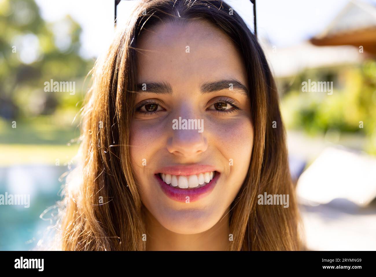 Portrait of smiling caucasian fit woman standing by pool in sunny garden Stock Photo