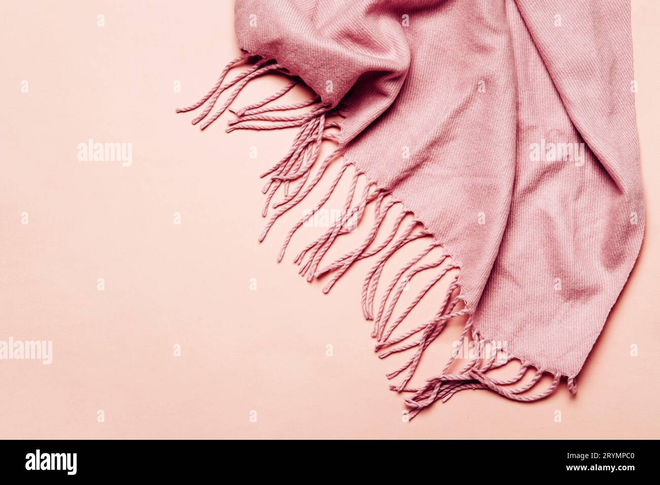 Pink cozy scarf with tassels on pastel background. Minimal winter or autumn background for your design Stock Photo