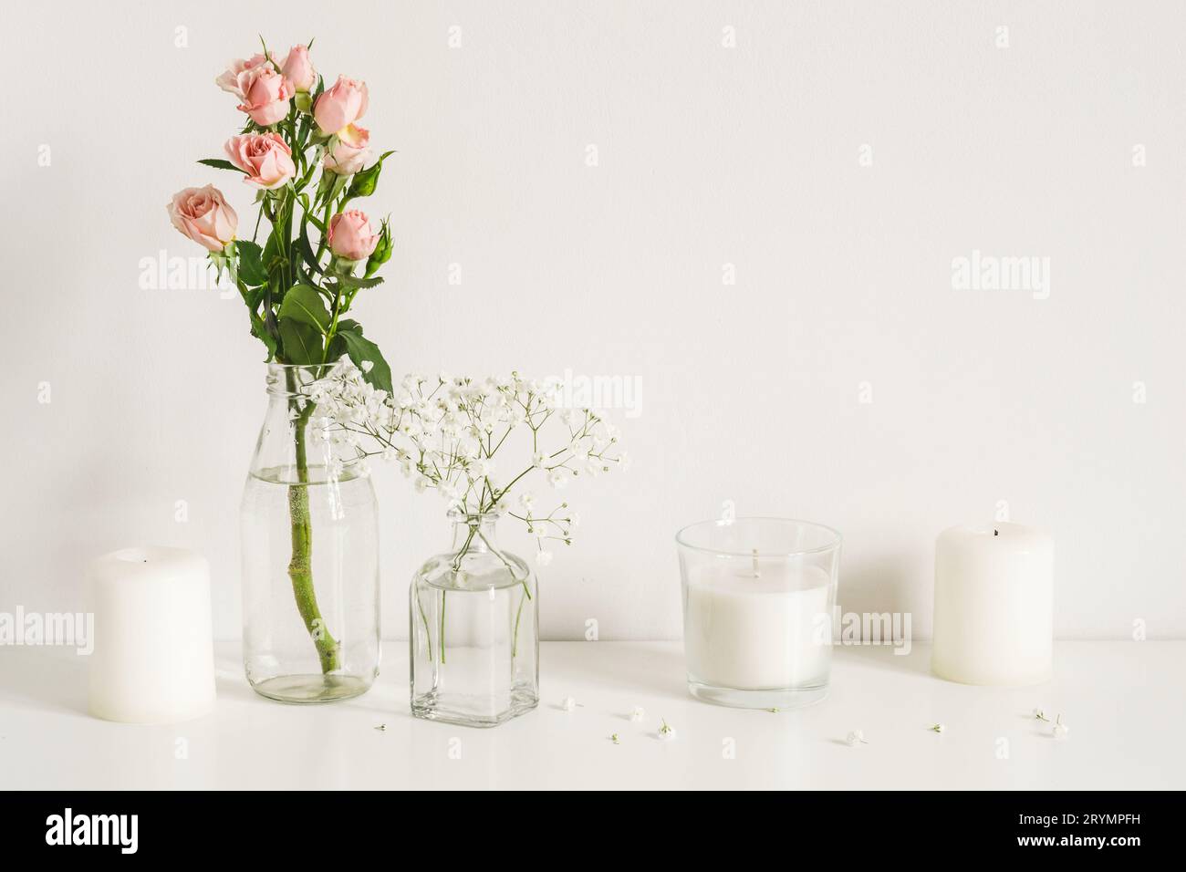 White arrangement of roses, baby's breath flowers and candles. Copy space for lettering Stock Photo