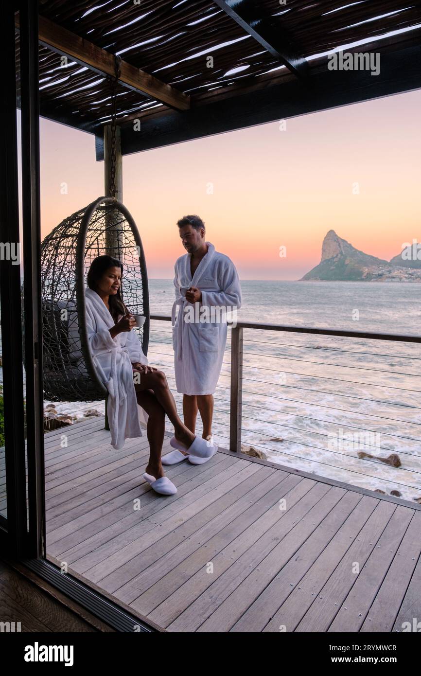 Couple man and women drinking coffee on the balcony during sunrise in Cape Town South Africa. Stock Photo