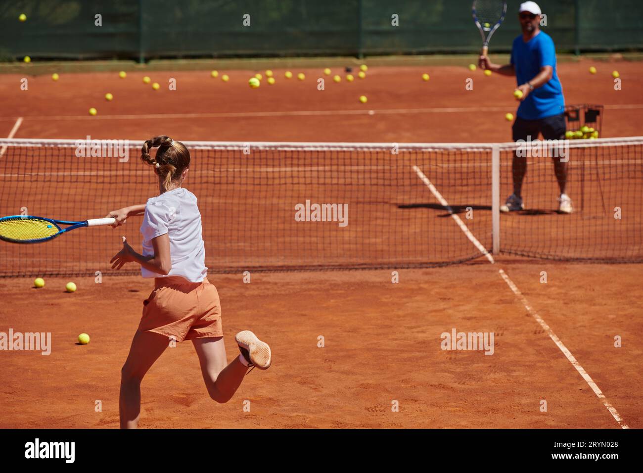 A professional tennis player and her coach training on a sunny day at
