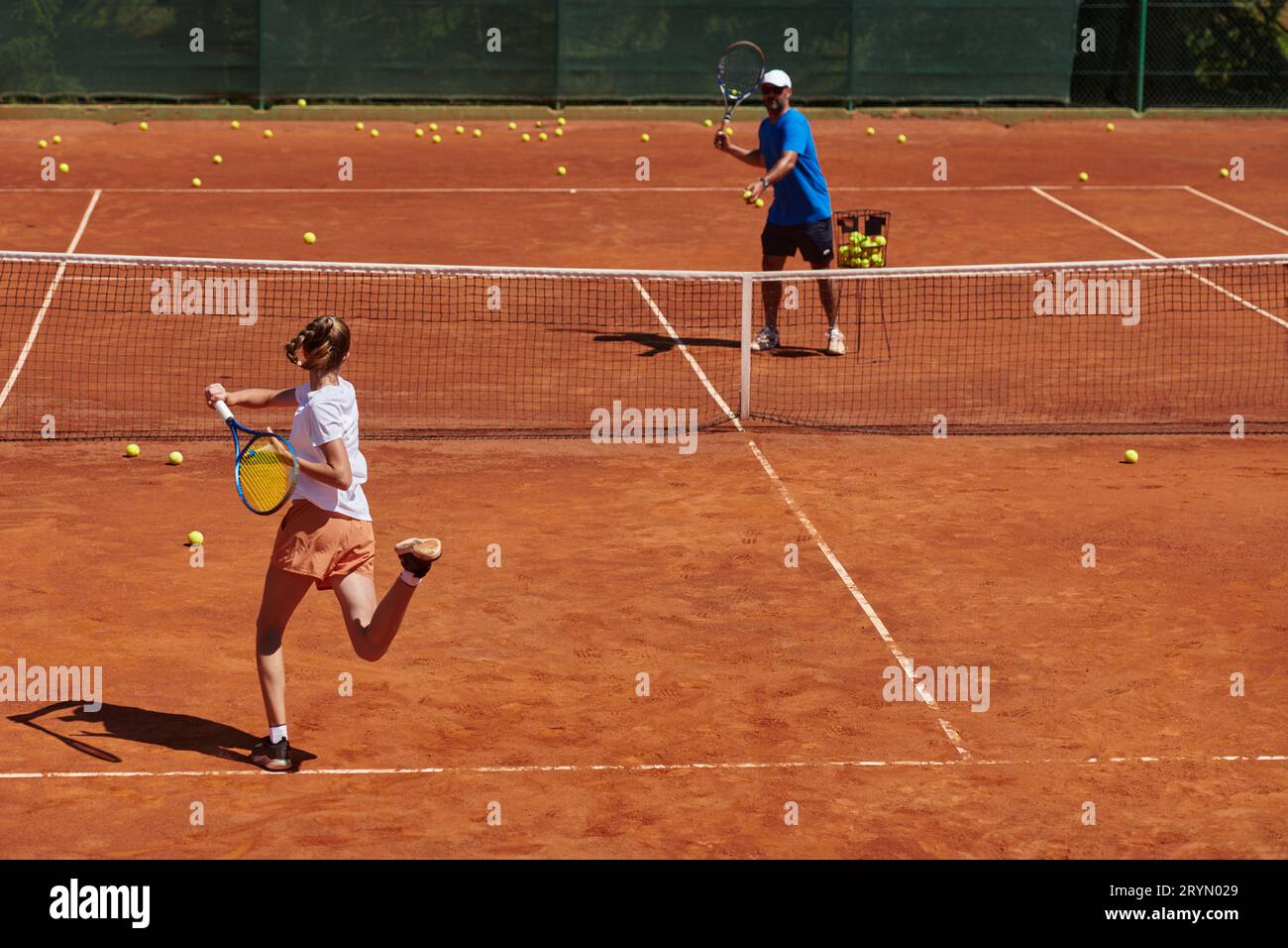 A professional tennis player and her coach training on a sunny day at