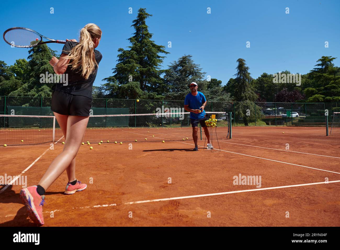 A professional tennis player and her coach training on a sunny day at
