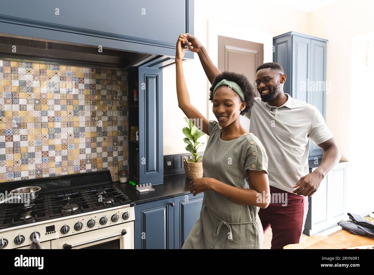 Happy african american couple having fun dancing together in kitchen ...